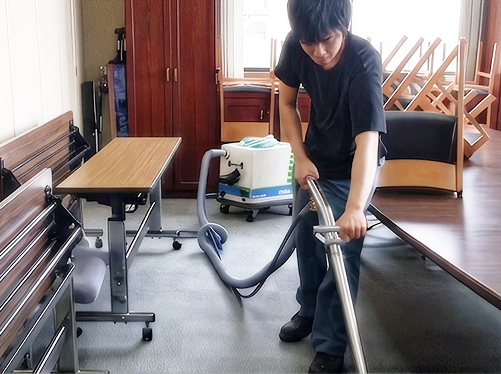 会議室でバキュームを使いカーペットを清掃するスタッフ
