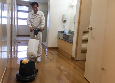 ポリッシャーでフローリングの廊下を洗浄するスタッフ