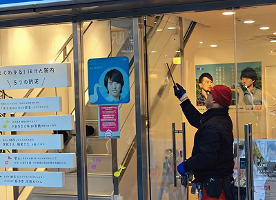 店舗のガラス面をスクイジーで清掃する作業員