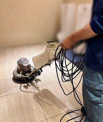 施工中：ポリッシャーでタイル床を洗浄する作業員