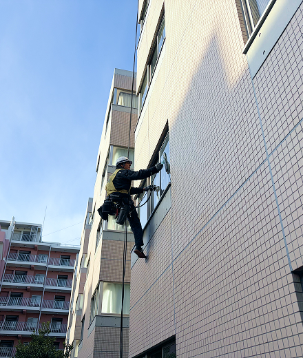 施工中：ロープで吊り下がりマンションの窓ガラスを清掃する作業員