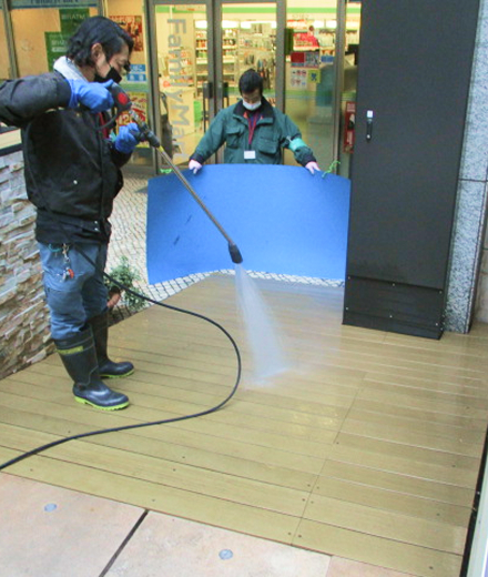 施工中：高圧洗浄機で屋外スロープの汚れを洗い流す2人の作業員
