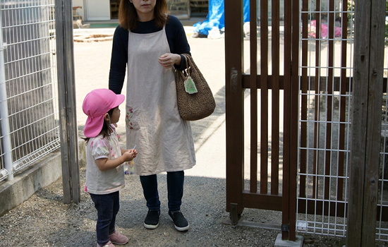 保育園の門の前で子どもを迎える母親