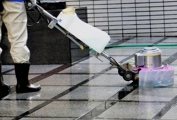 ポリッシャーで石張りの床を洗浄する作業員
