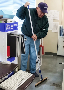デッキブラシで事務所の床を清掃するスタッフ